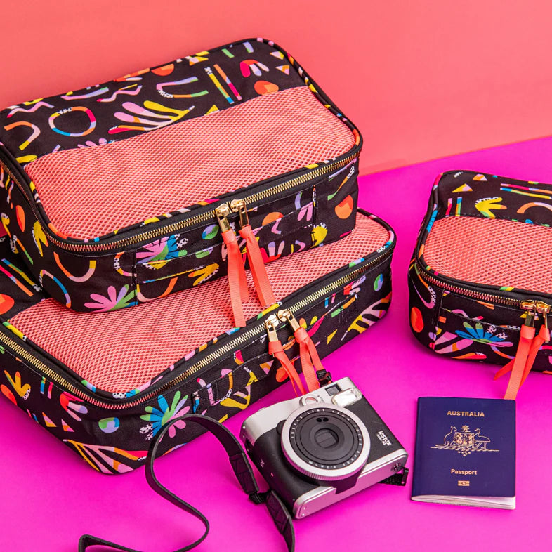 Rainbow packing cubes next to passport and camera.